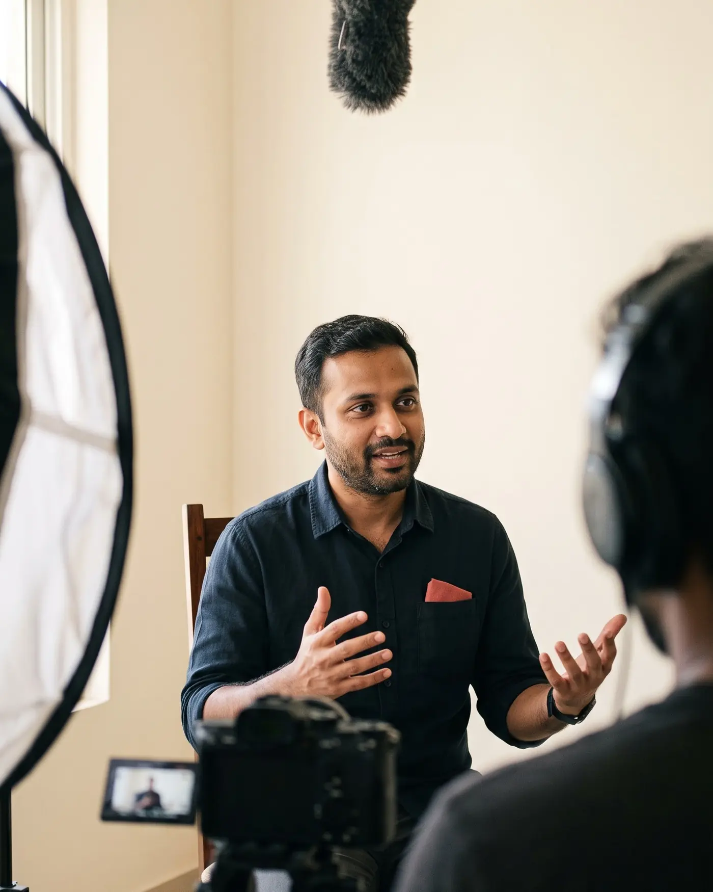A founder mid-answer to camera, boom microphone overhead and a softbox out of focus in the foreground